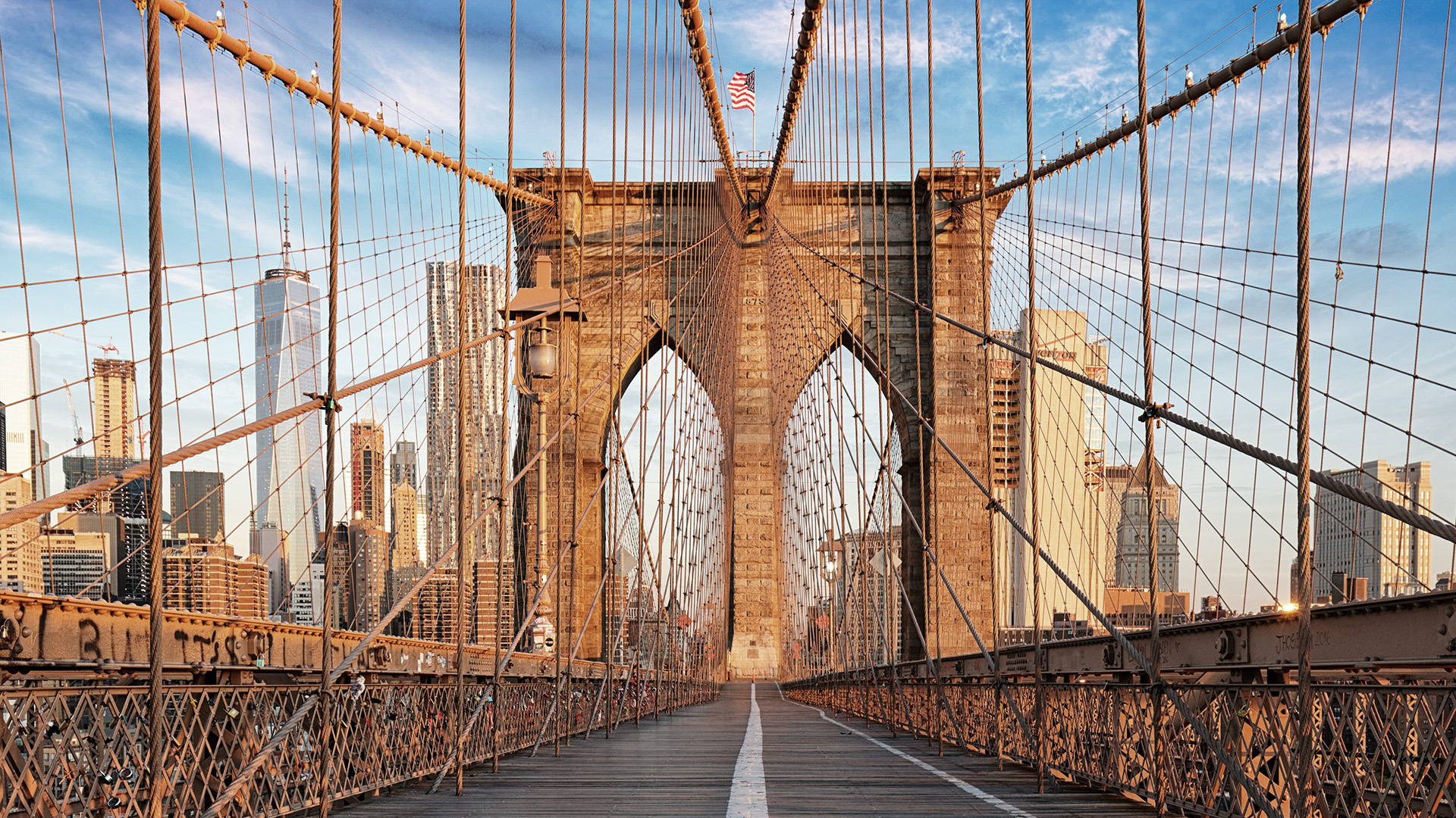 The image shows the Brooklyn Bridge, a famous suspension bridge in New York City, with its iconic arches and cables against a backdrop of the city skyline.